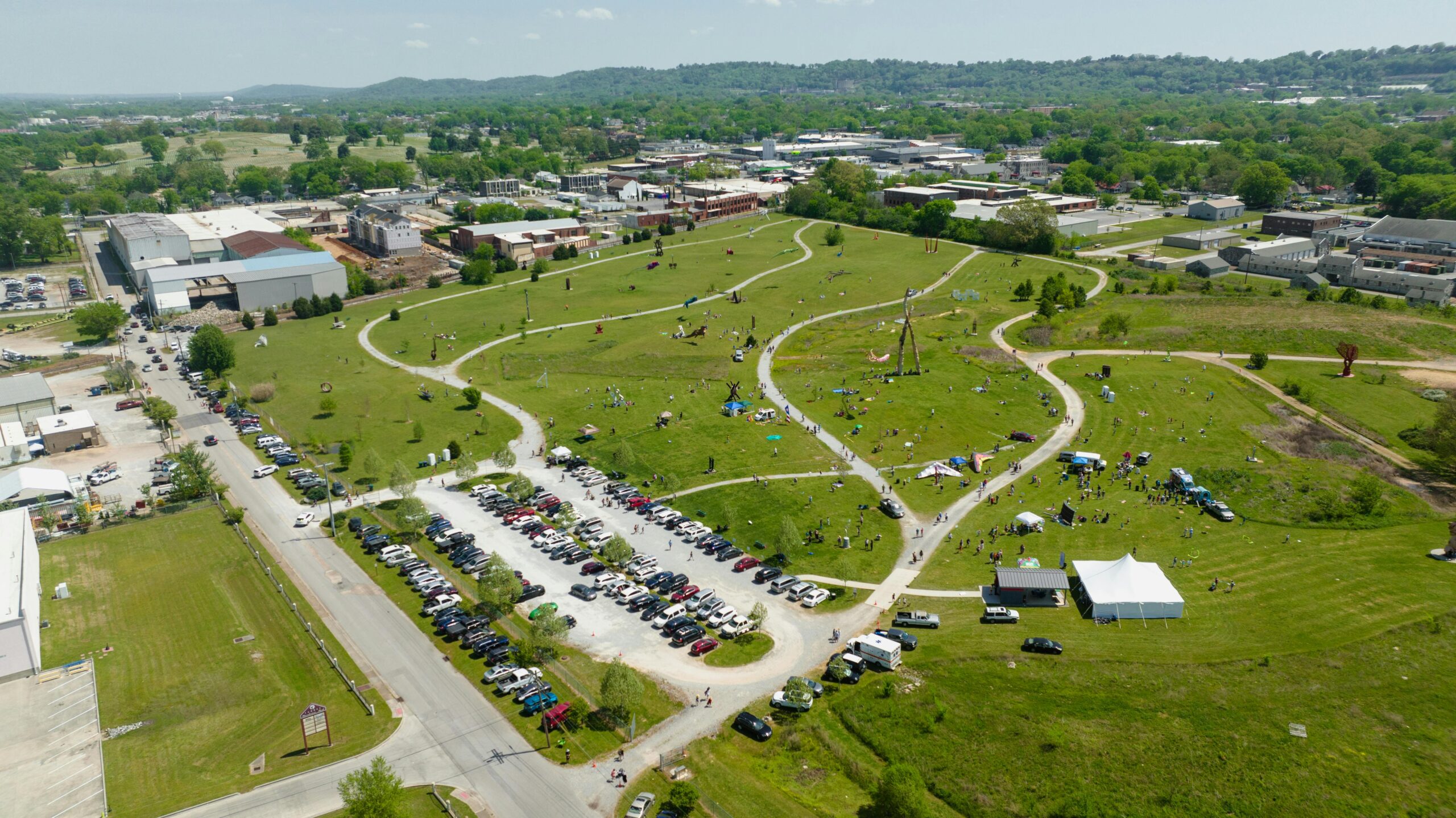 Aerial view of a bustling park with pathways and parked cars in Chattanooga, TN.