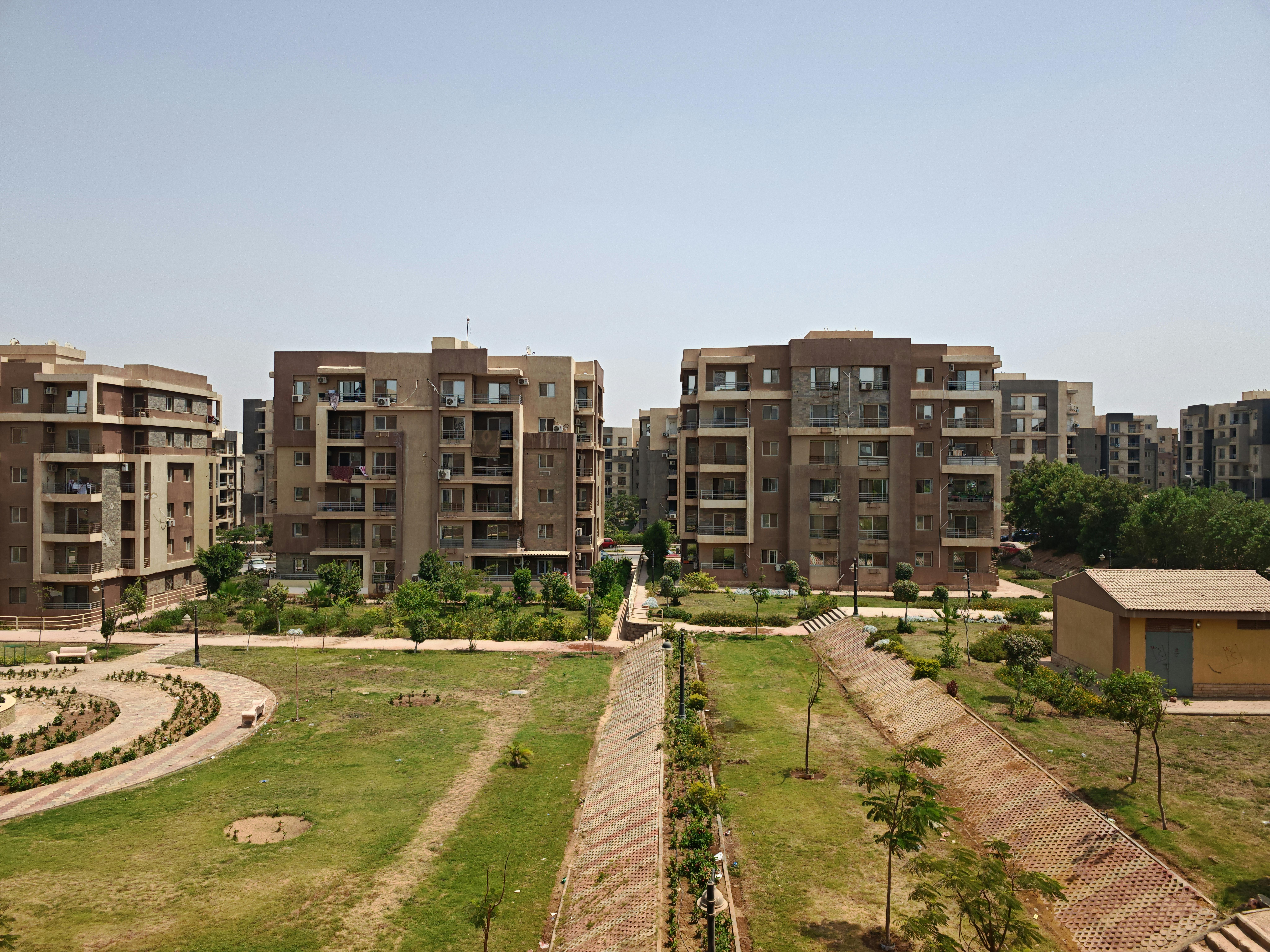 Aerial view of modern apartment buildings surrounded by lush greenery on a sunny day.