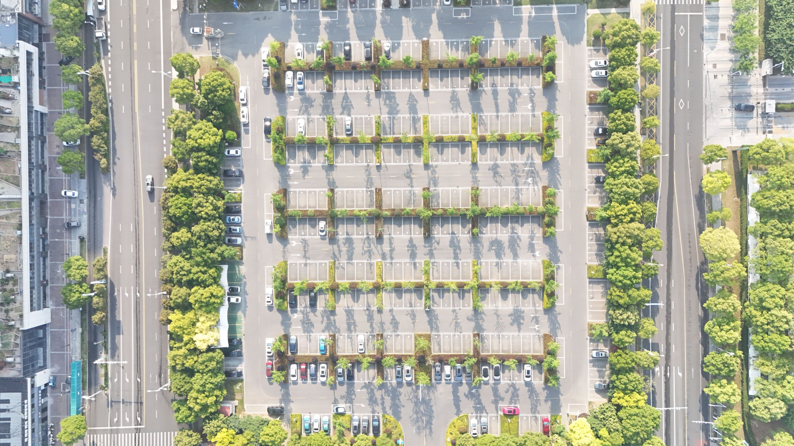 Aerial view showcasing an organized city parking lot lined with trees and parked cars.